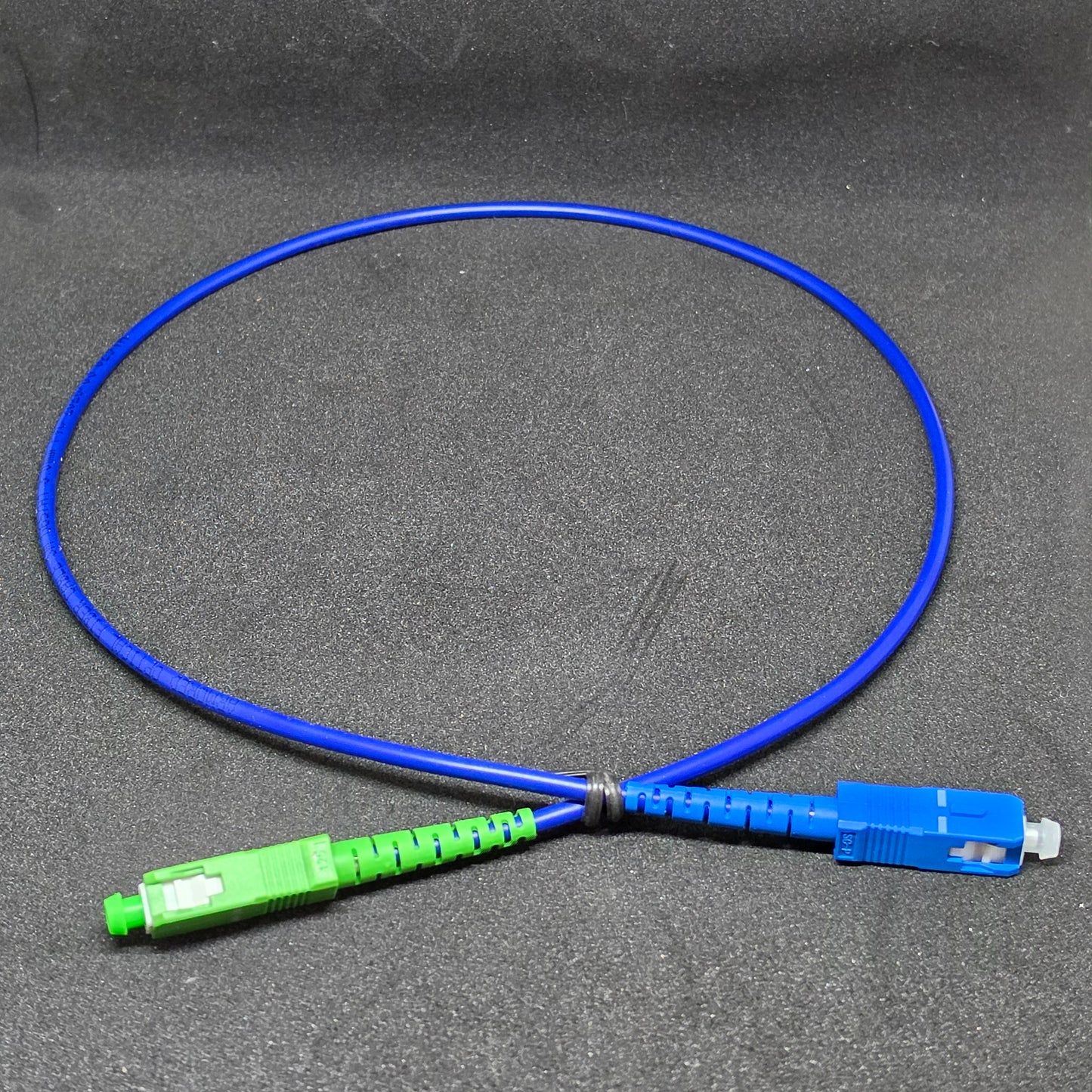Blue fiber optic cable with green and blue connectors on a gray background