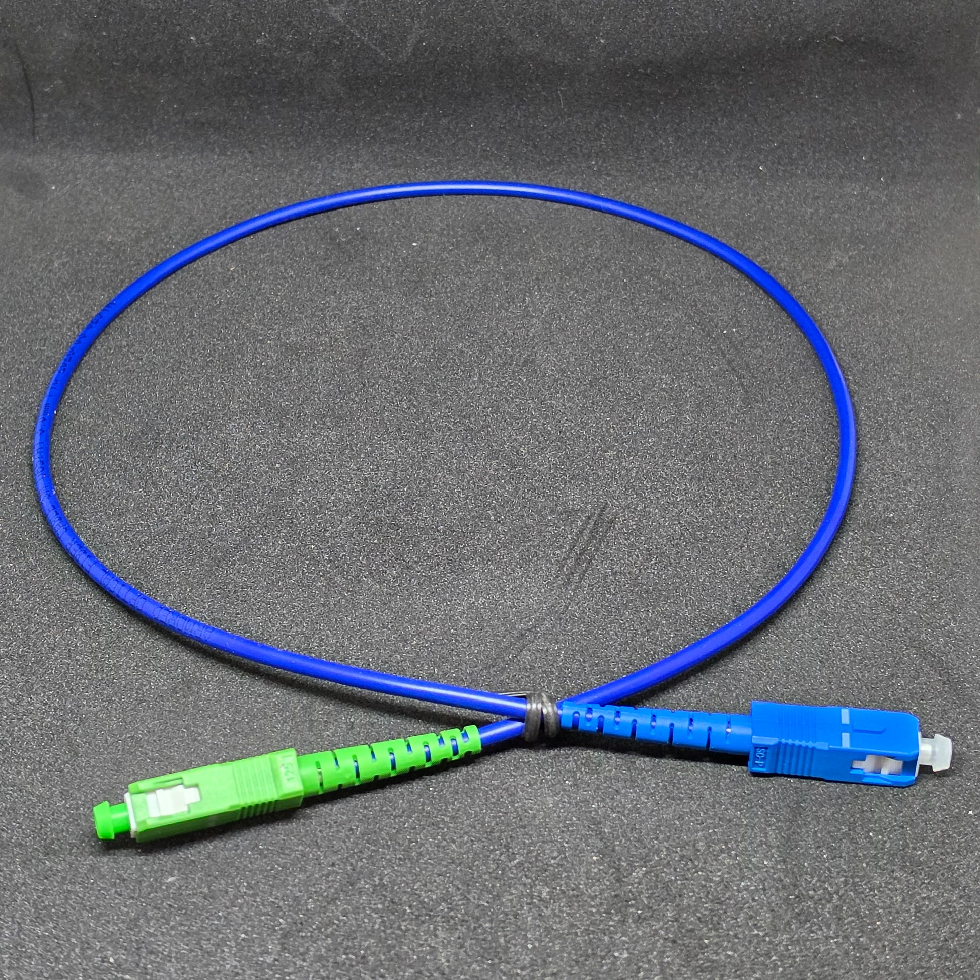 Blue fiber optic cable with green and blue connectors on a gray background