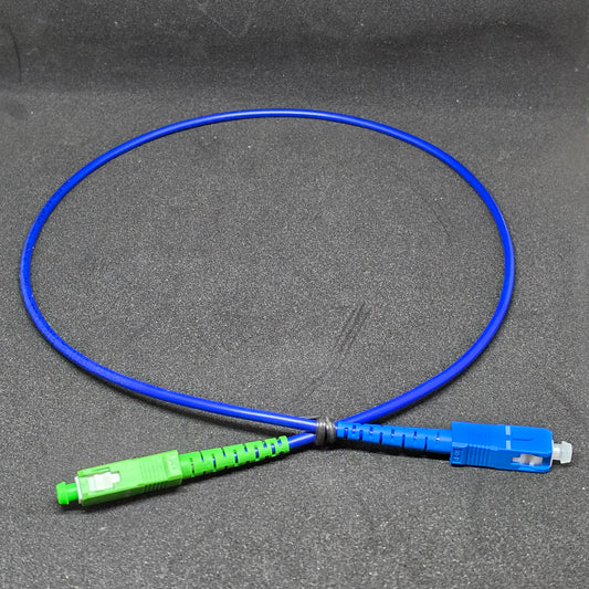 Blue fiber optic cable with green and blue connectors on a gray background